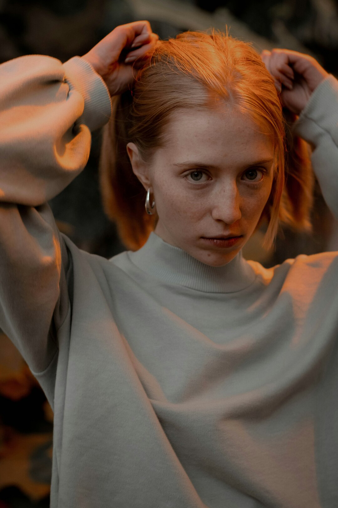 Portrait of a woman with short red hair wearing a light sweater